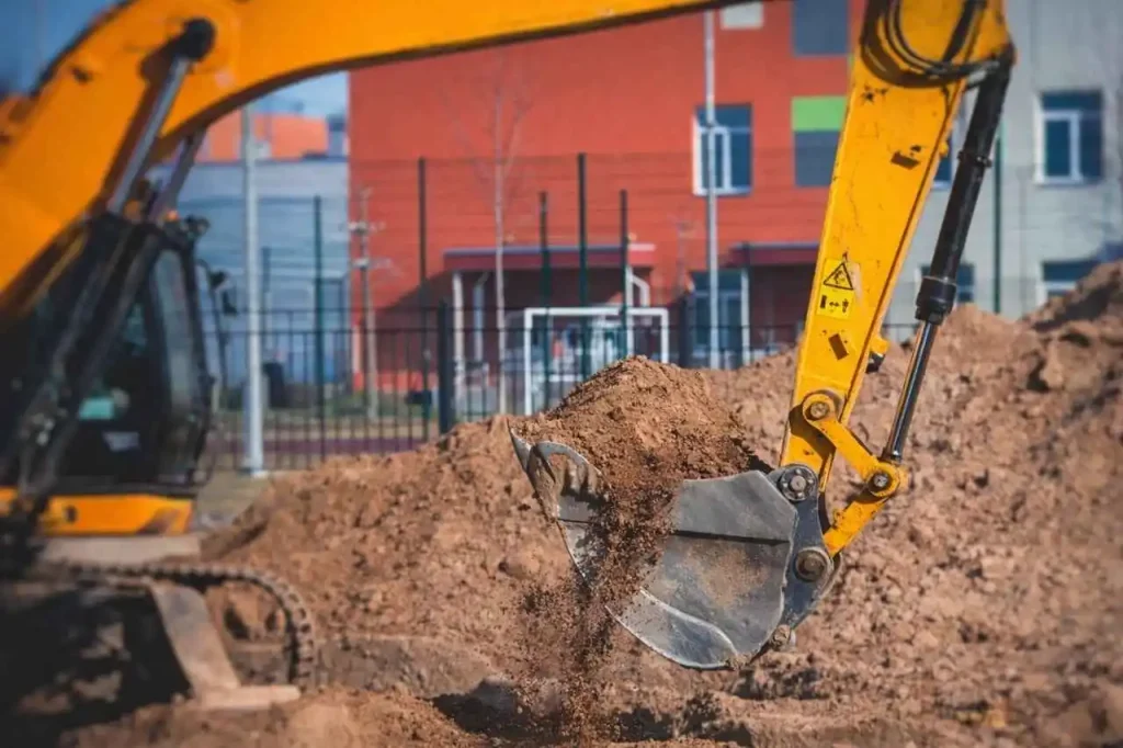 Excavator scooping soil at commercial development site during civil earthworks in Epping VIC.