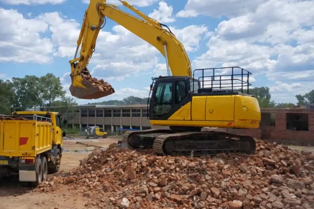 Excavator loading rubble into tipper truck during demolition and earthworks project in Mickleham Victoria.